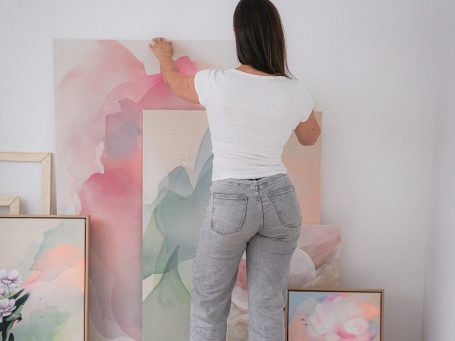 Anca Juliana hält ein abstraktes Kunstwerk vor sich, umgeben von weiteren Bildern.