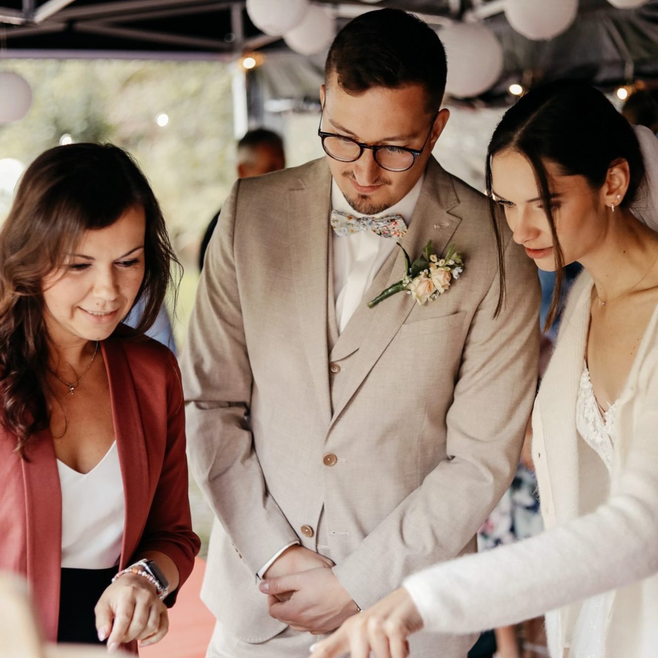 Künstlerin und Brautpaar betrachten gemeinsam eine Leinwand bei einer Hochzeit.