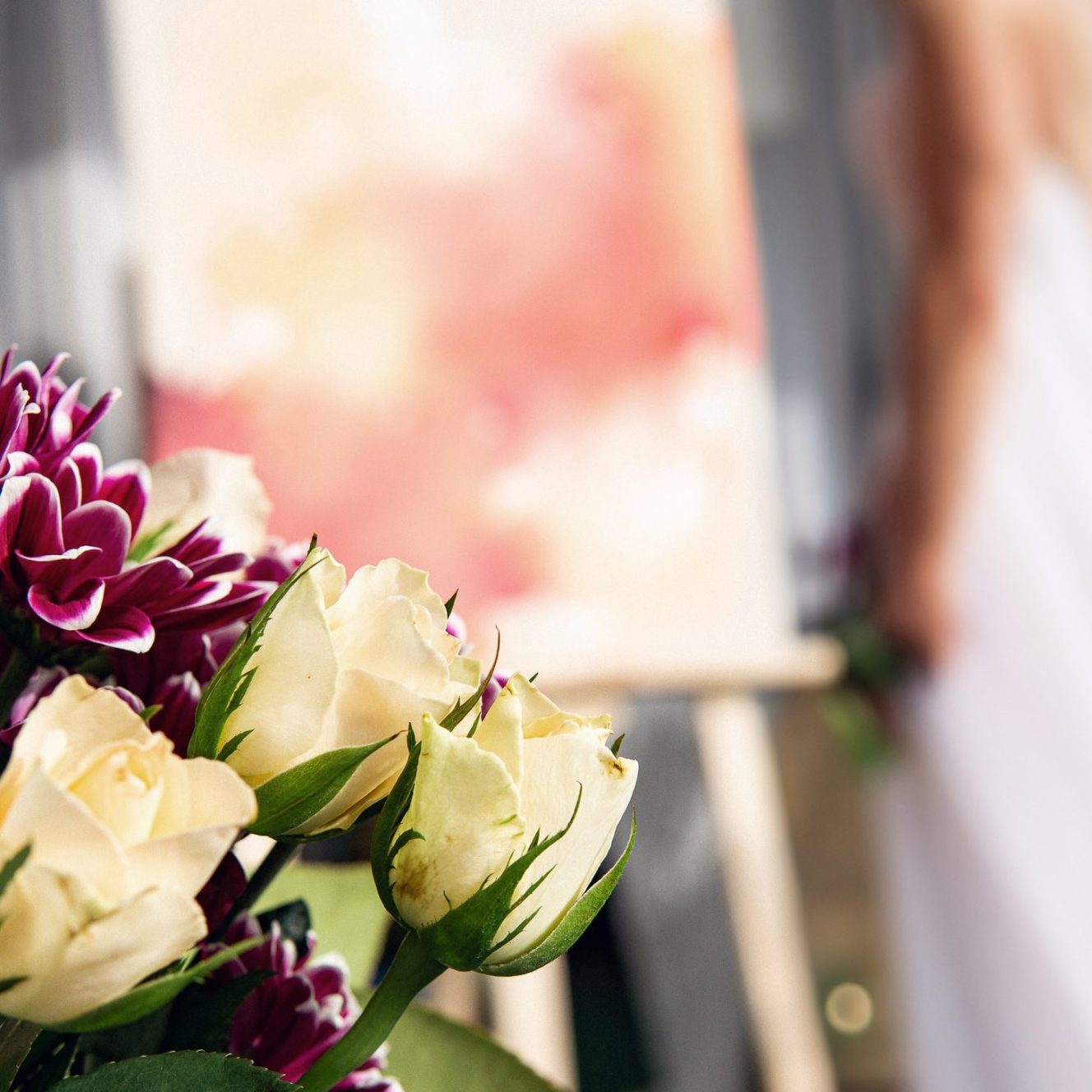 Braut mit Hochzeitsblumen im Vordergrund, unscharfer Hintergrund mit Malerei.