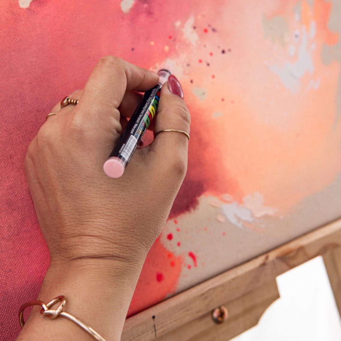 Eine Hand zeichnet mit einem Stift auf eine farbenfrohe, Leinwand