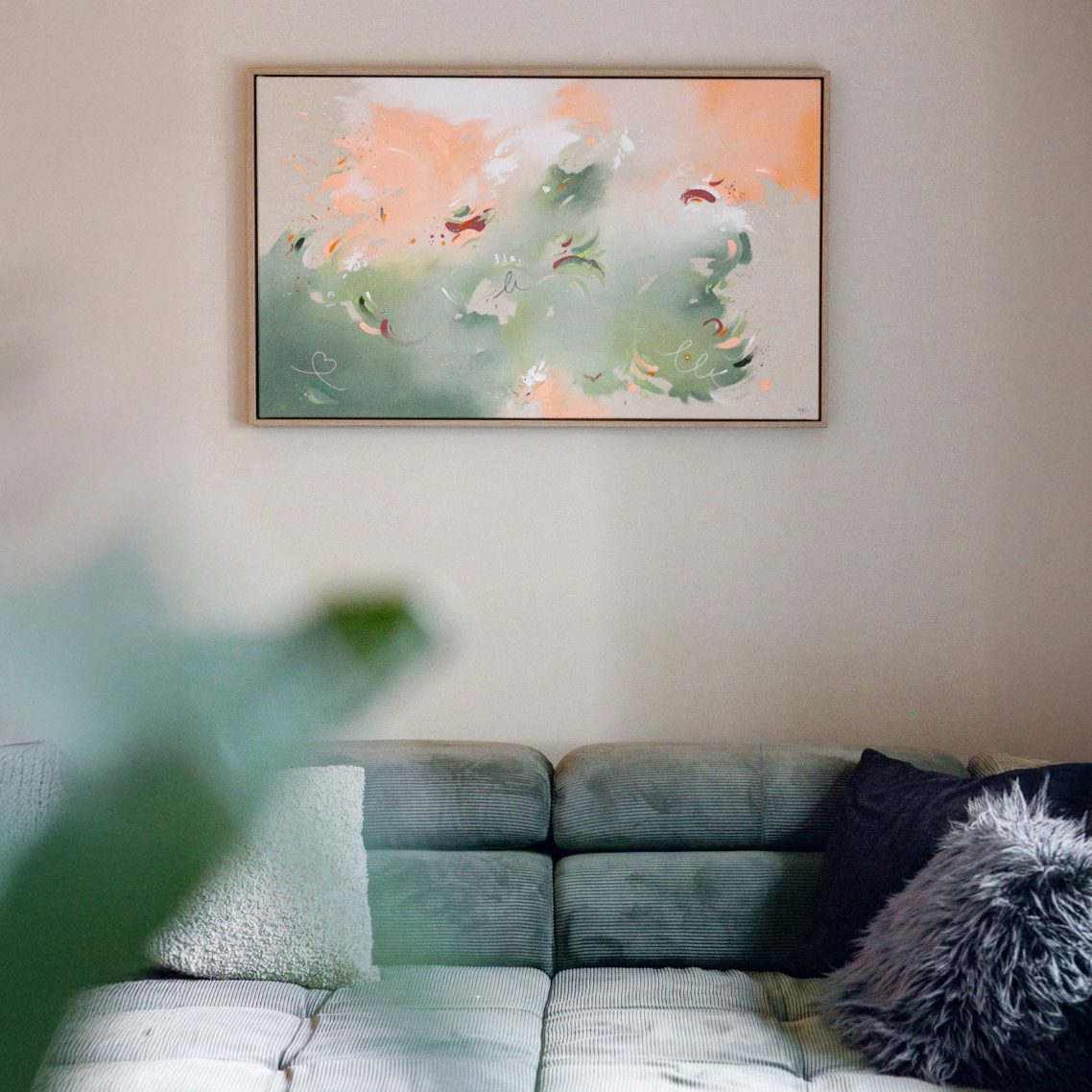 Abstrakte Malerei mit sanften Farben, hängend über einer gemütlichen Couch.