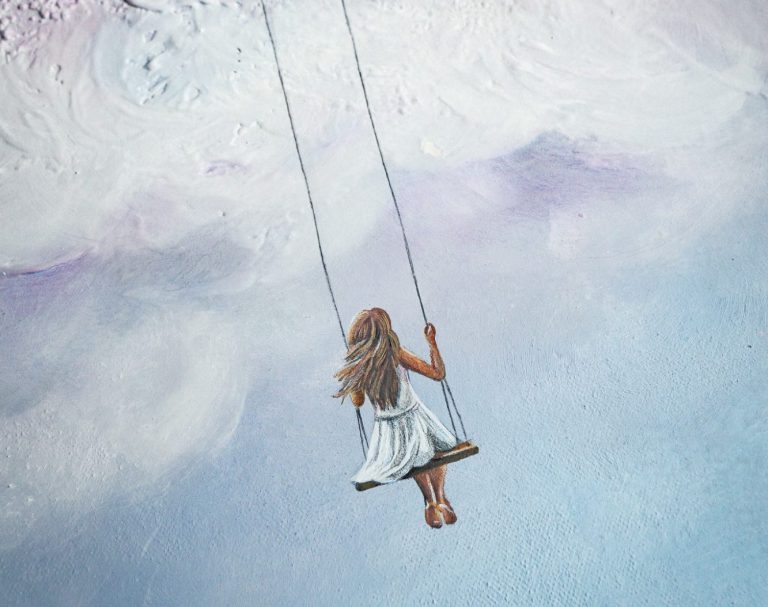 Ein Mädchen in einem weißen Kleid schwingt in den Himmel auf einer Schaukel.