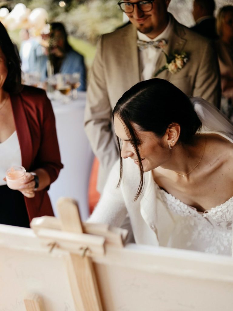 Eine Braut in einem eleganten Kleid, während sie an einem Kunstwerk malt.