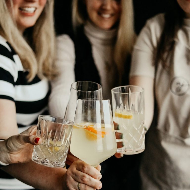 Gruppe von Personen, die in einer Bar miteinander sprechen und Getränke halten.